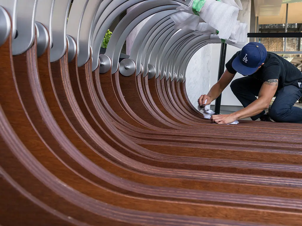 Hand-finishing the laminated wood ribs of a sculptural bike carousel