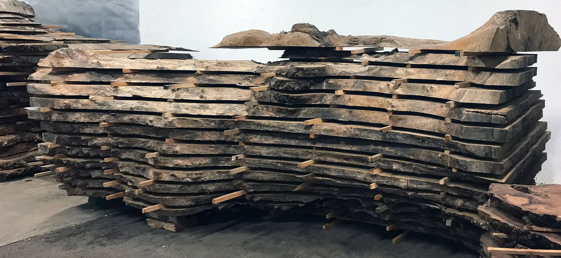 Live-edge hardwood slabs stacked and stickered for drying at the Chapel Arts shop