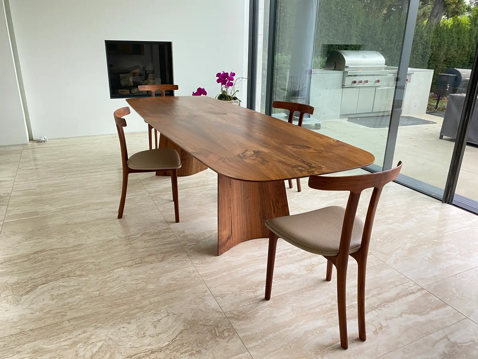 Swell dining table and sculpted solid-walnut chairs installed in a modern home