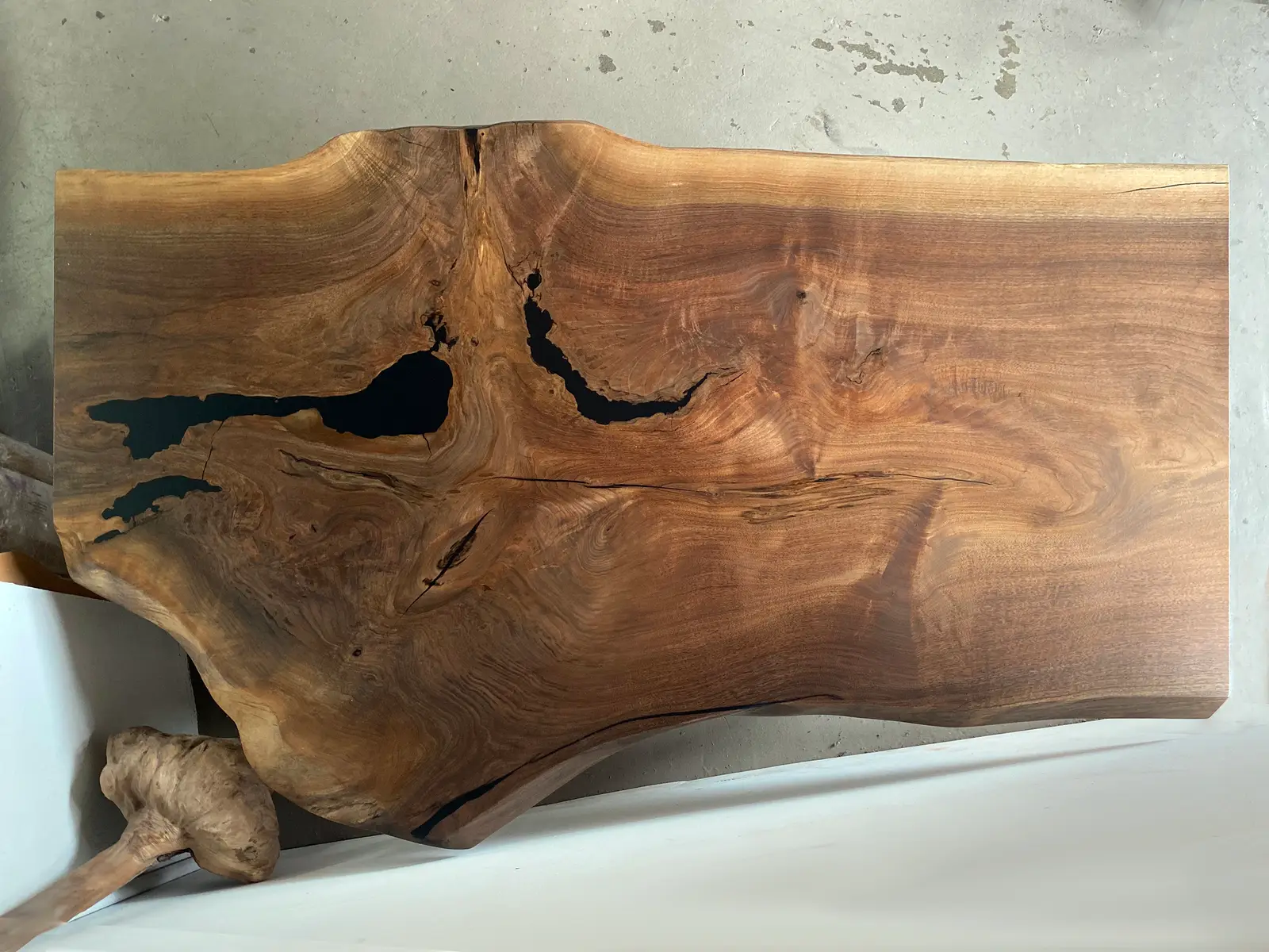 Glassy walnut slab panel with resin-filled voids, destined for a wine cellar